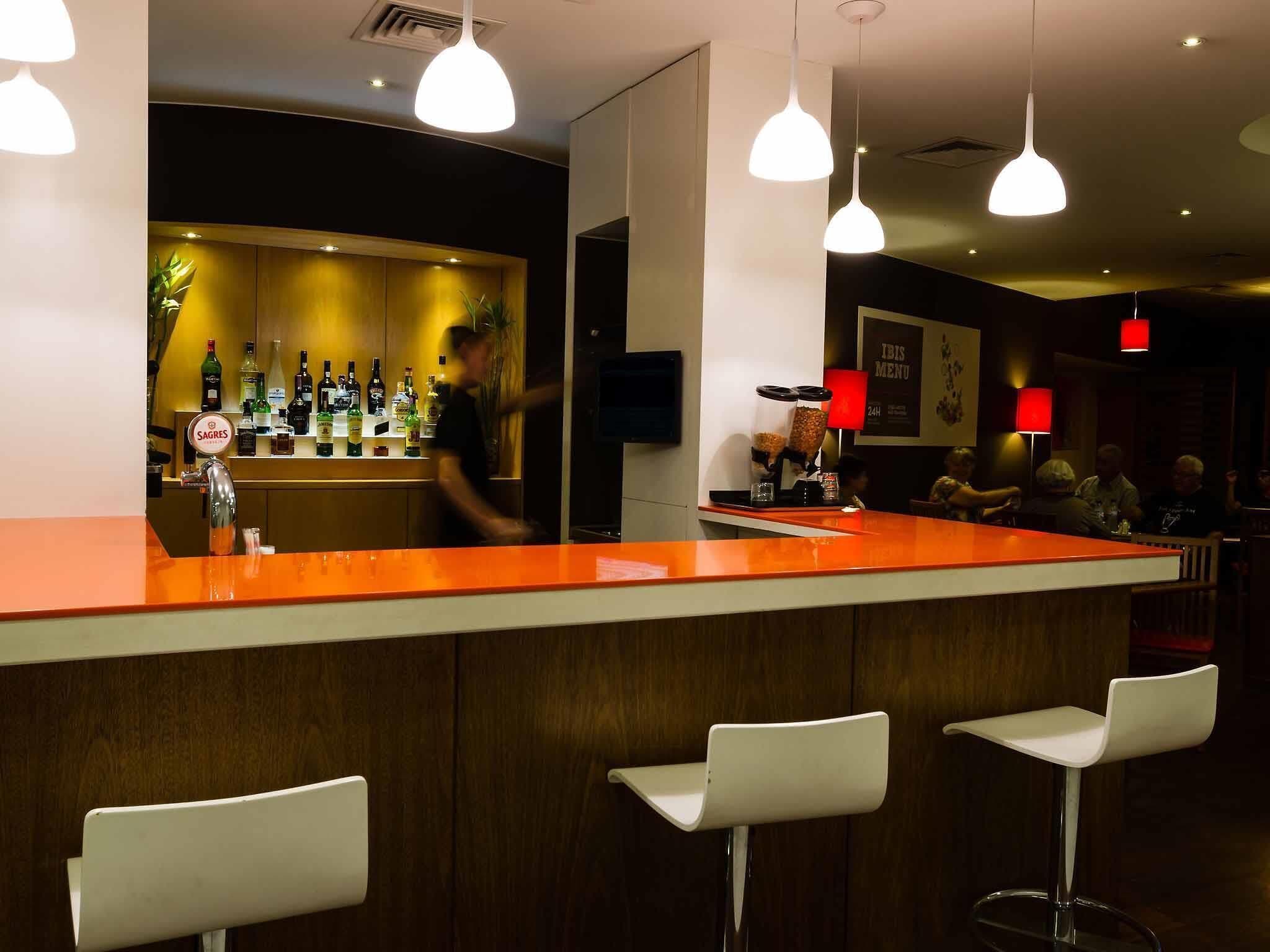 A bar area with a counter, stools, and a person serving.