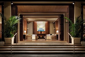 A hotel lobby with a reception desk, seating area, and a large painting on the wall. - Halekulani (Honolulu)