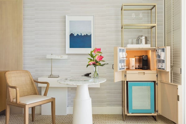A compact room with a small table, a chair, a cabinet with a blue door, and a framed picture on the wall.
