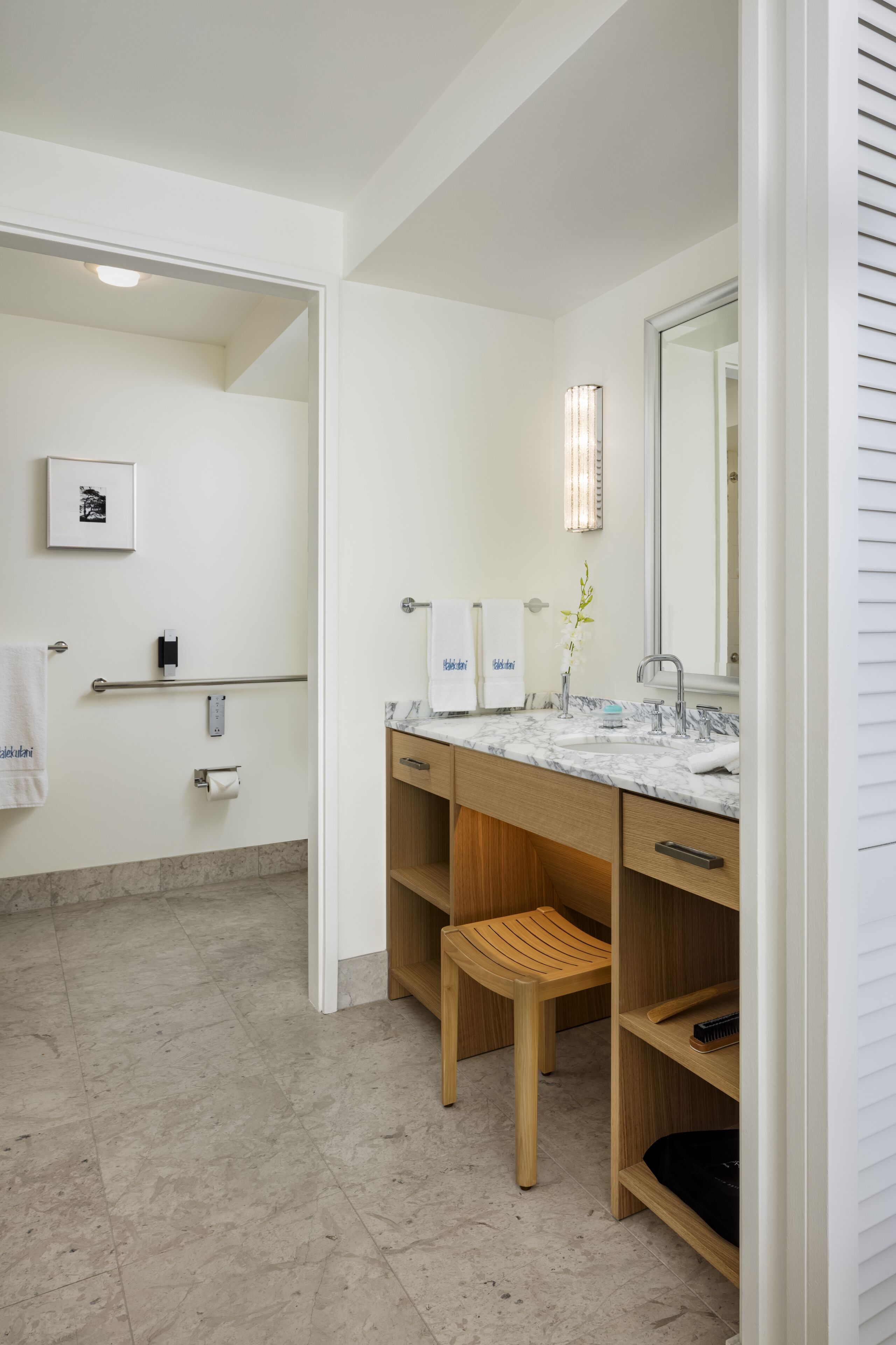 A modern bathroom with a marble sink, wooden vanity, and a large mirror.
