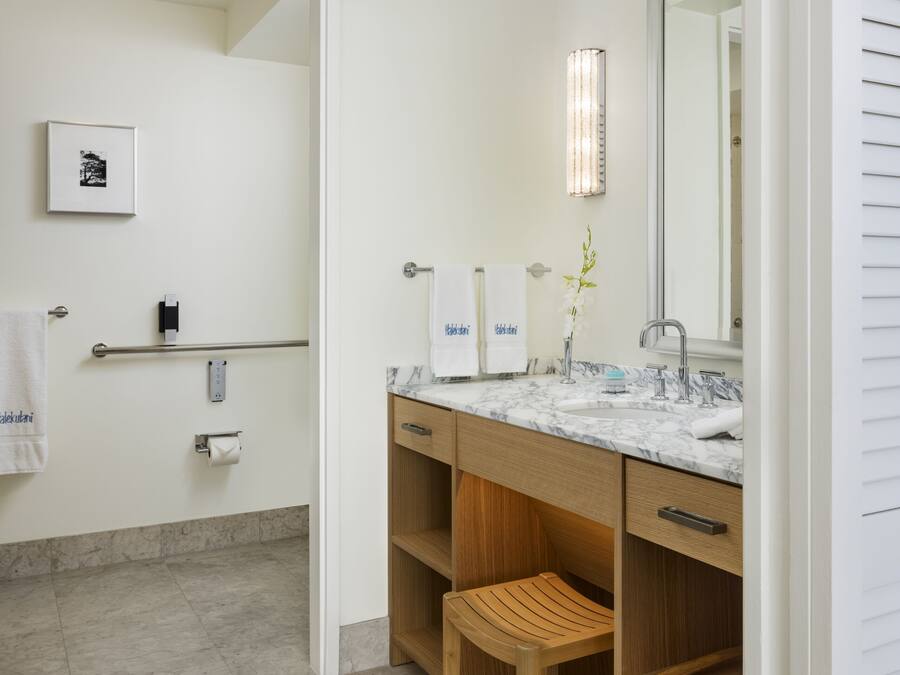 A modern bathroom with a marble sink, wooden vanity, and a large mirror.