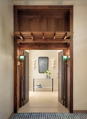 A wooden entryway with a console table, two wall sconces, and a framed artwork above.
