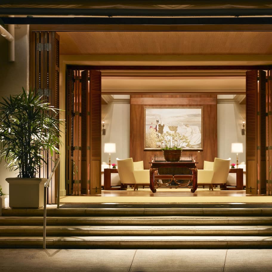 A lobby with a reception desk, two armchairs, a coffee table, and a large painting on the wall.