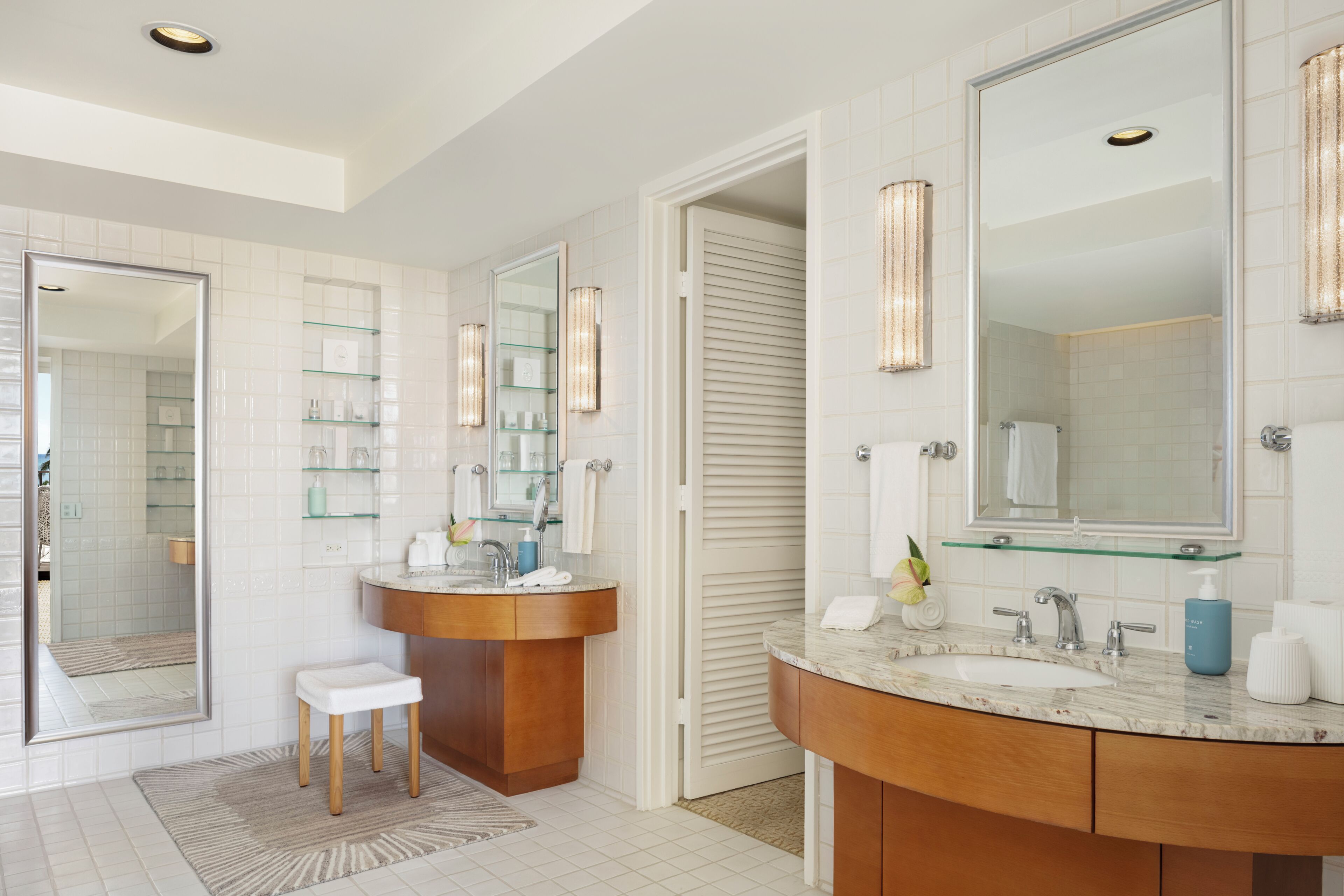 A modern bathroom with a vanity, a mirror, and glass shelves.