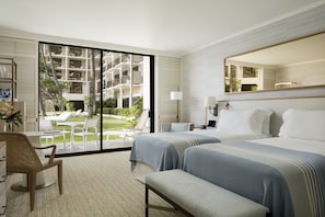 A modern hotel room with a large sliding glass door leading to a balcony with outdoor seating.