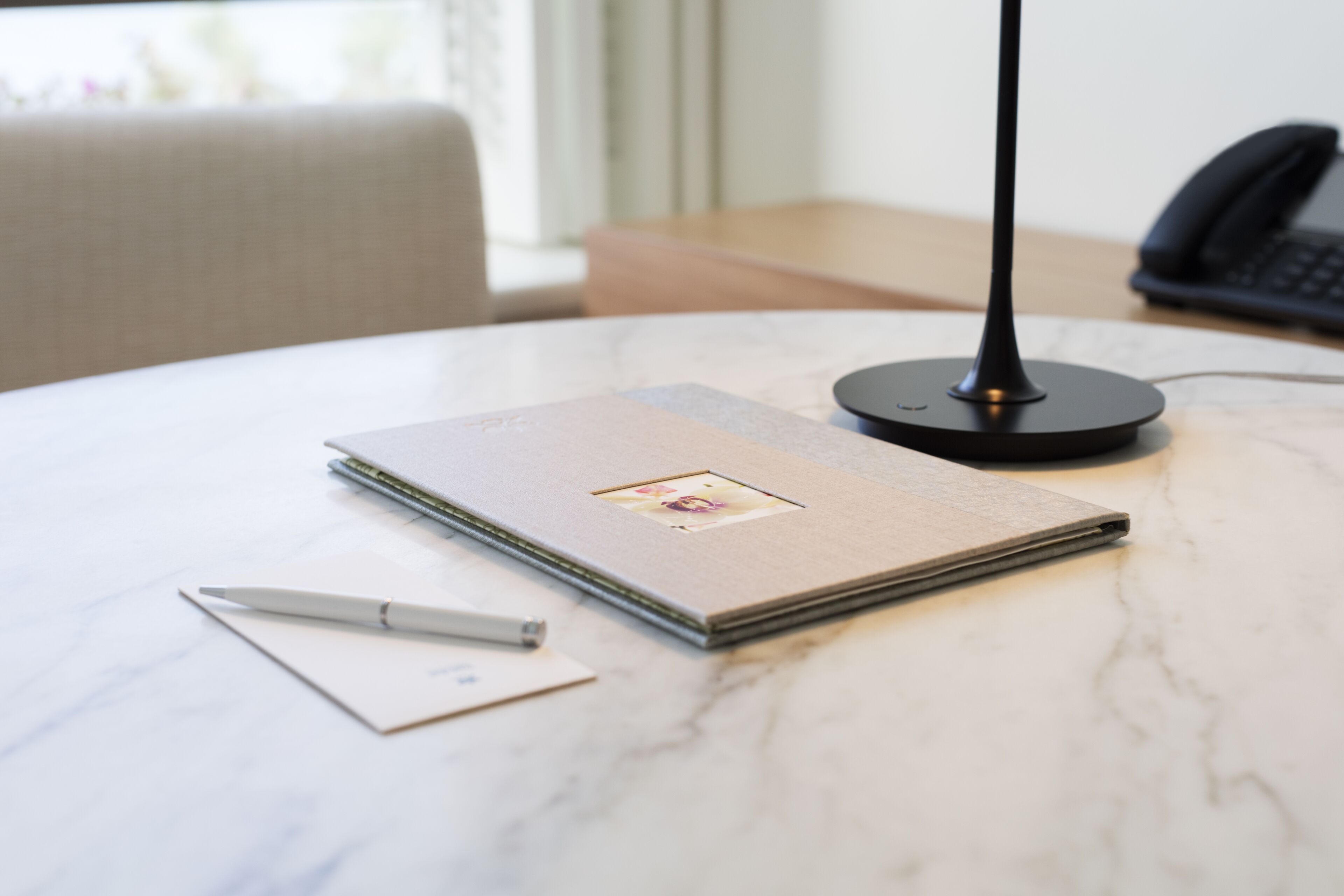 Ein ordentlich eingerichteter Arbeitsplatz mit Notizbuch, Stift und einer Lampe auf einer Marmortafel.
