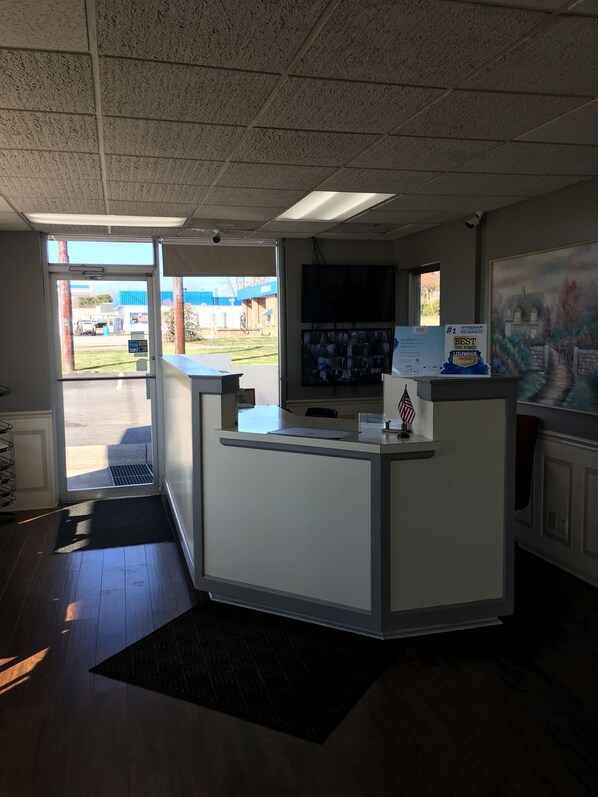 A reception desk with a flat-screen TV, a framed award, and a view of the outside.