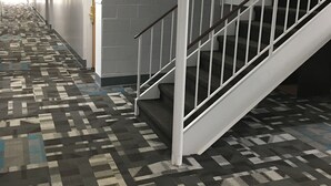 A hallway with a patterned carpet, a staircase with white railings, and a door with a sign. - Travelodge by Wyndham Gallipolis (Gallipolis)
