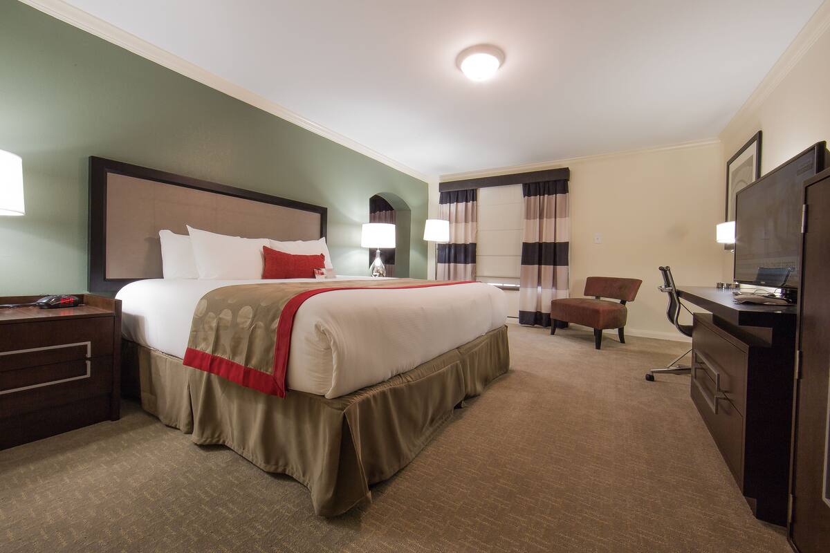 Een hotelkamer met een groot bed, een bureau, een stoel en een televisie.