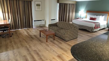 Una habitación de hotel con cama, sofá, escritorio y una mesita.
