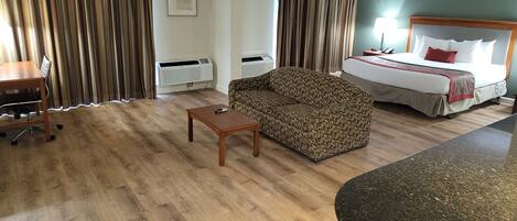 A hotel room with a bed, a sofa, a desk, and a small table.