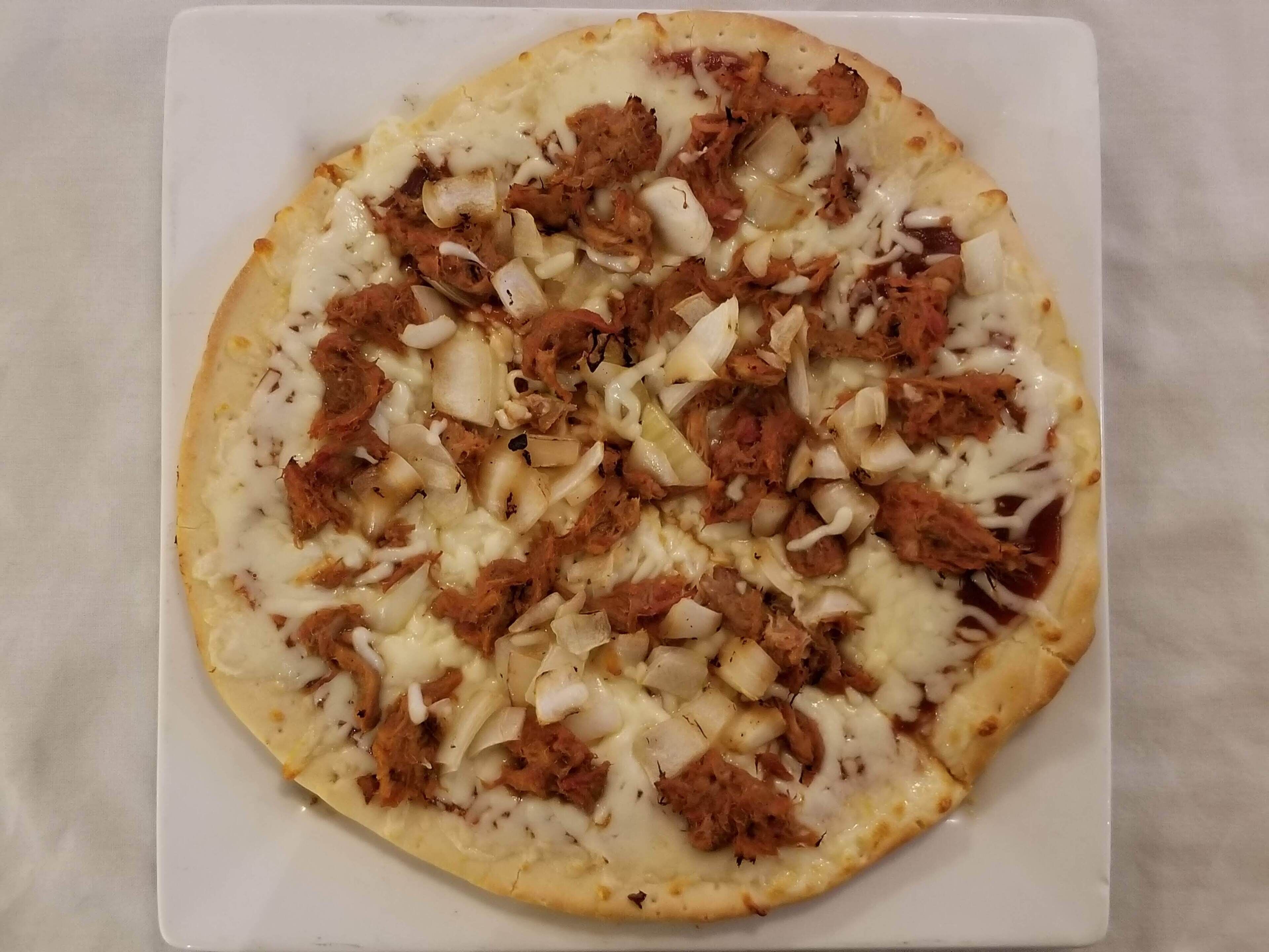 Eine Pizza mit Belag auf einem weißen Teller.