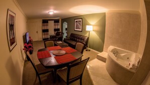 A hotel room with a dining area, a living room, and a bathroom.