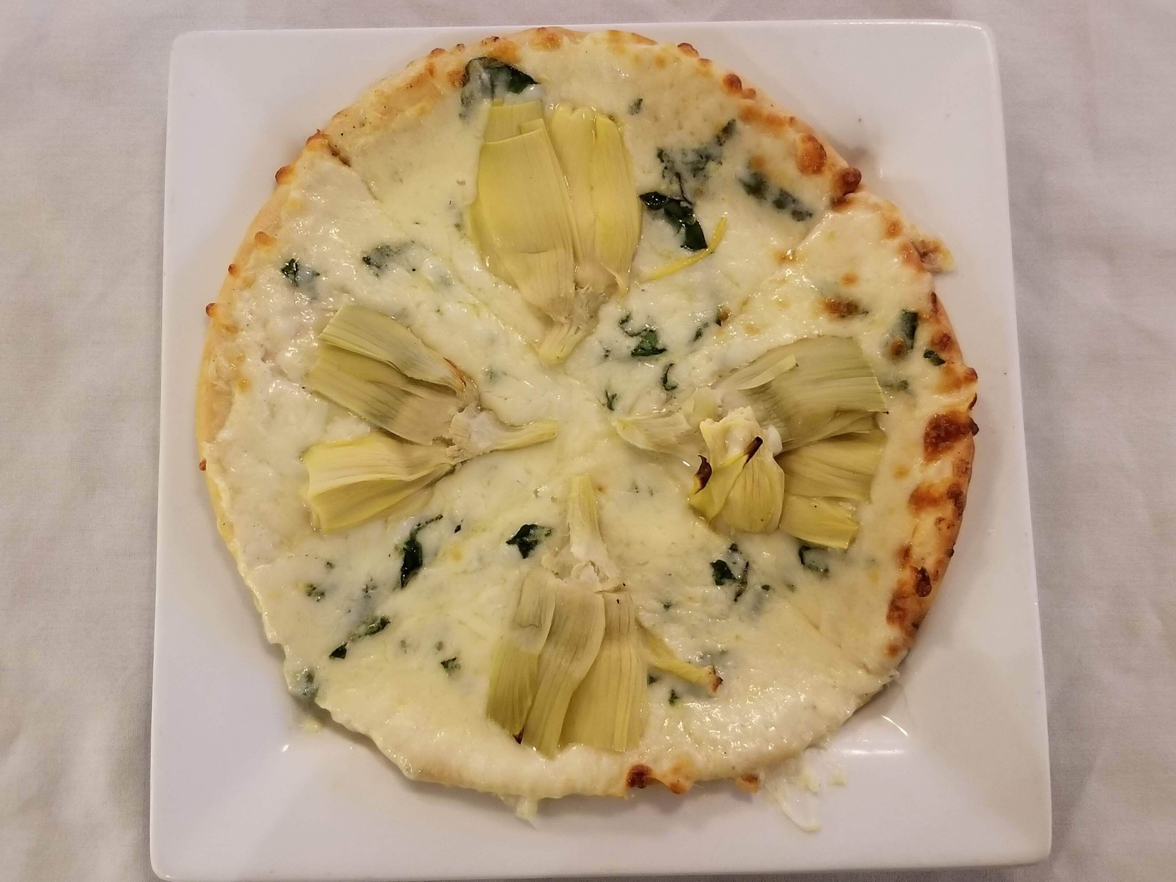 A pizza with artichoke hearts and spinach on a white plate.