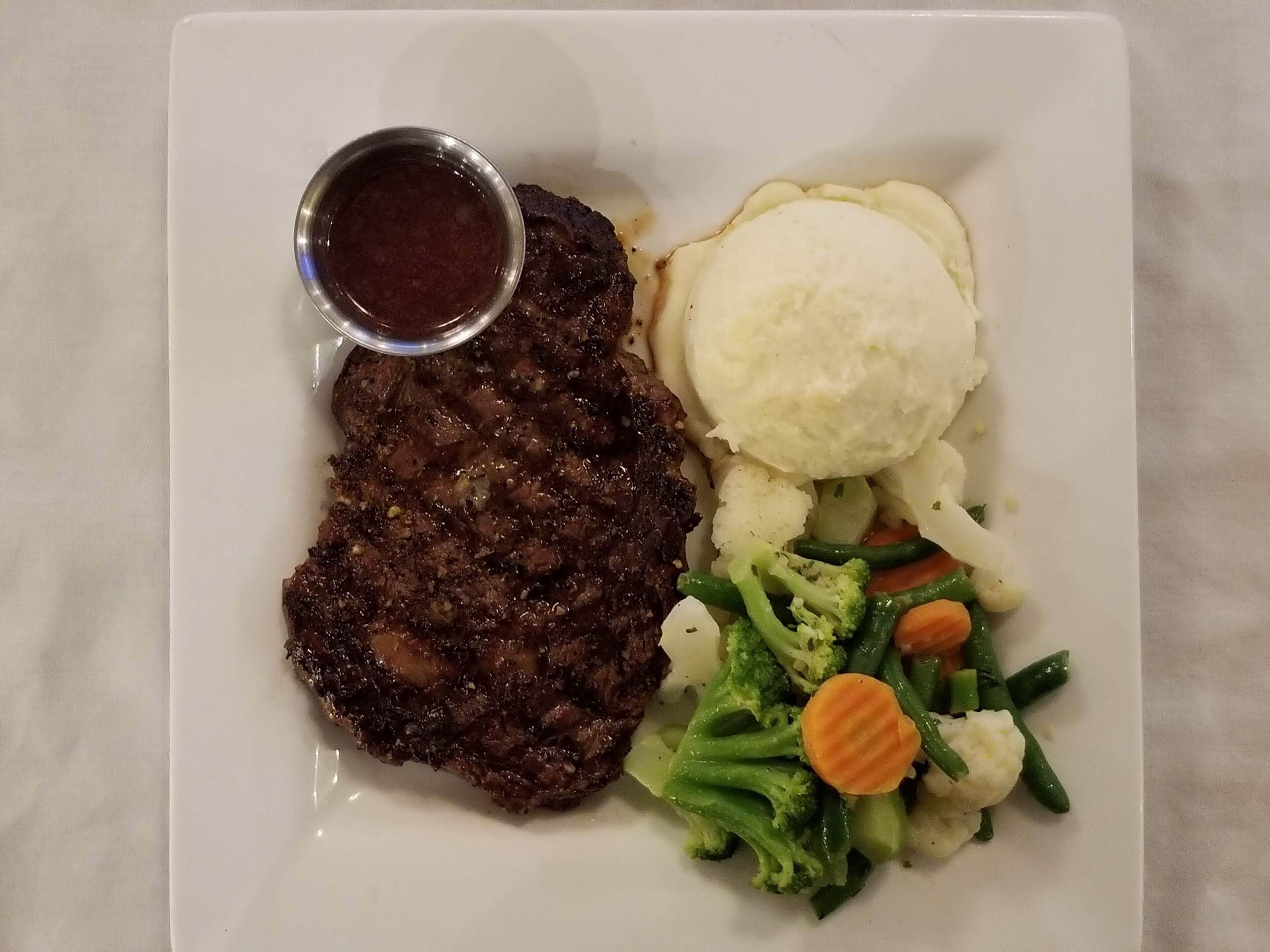 A plate with a steak, mashed potatoes, and a side of mixed vegetables.