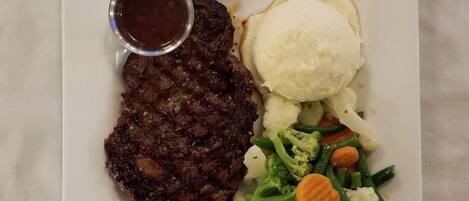 A plate with a steak, mashed potatoes, and a side of mixed vegetables.