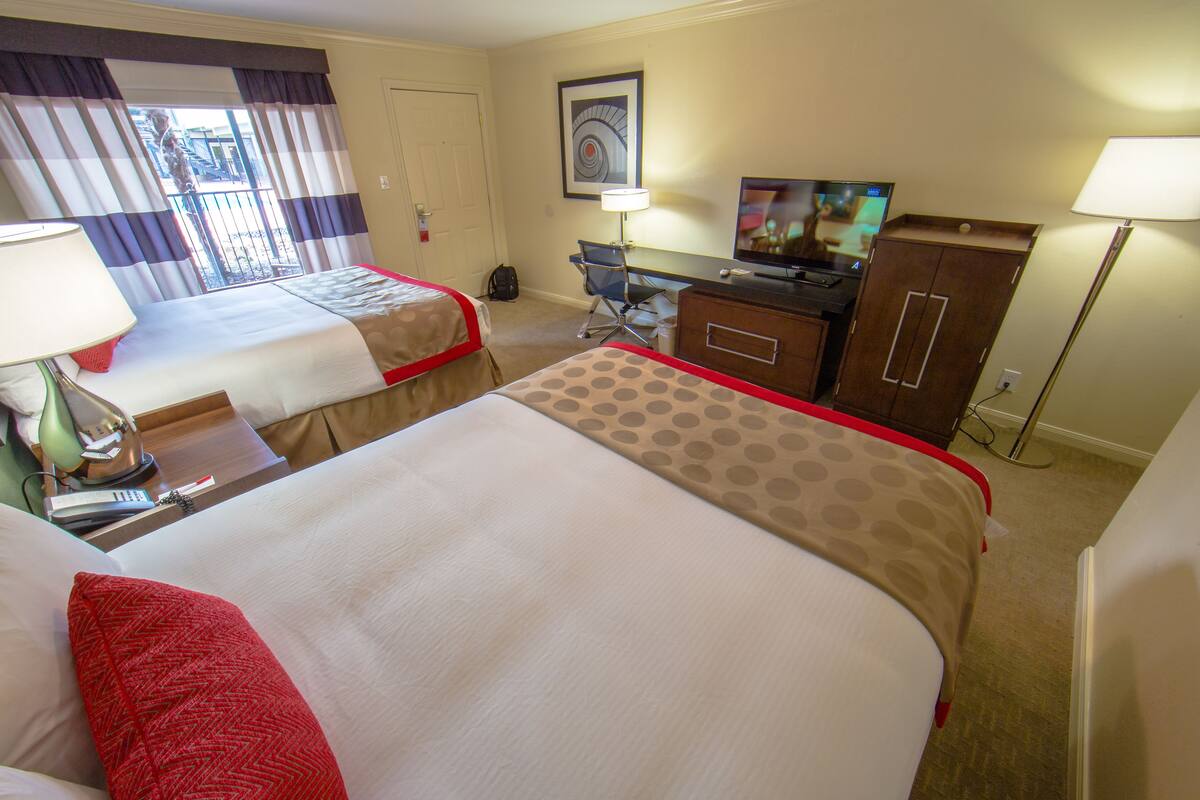 Een hotelkamer met twee bedden, een bureau, een televisie en een kledingkast.