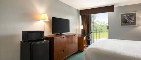 Een hotelkamer met een bed, een bureau met een televisie, een magnetron en een raam met uitzicht.