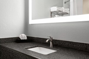 Un baño con encimera de granito, un lavabo y un espejo encima.