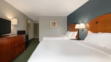 Een hotelkamer met twee bedden, een houten dressoir, een flatscreen televisie en een ingelijst schilderij aan de muur.