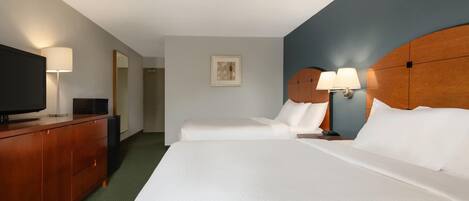 Habitación de hotel con dos camas, un aparador de madera, un televisor de pantalla plana y un cuadro en la pared.