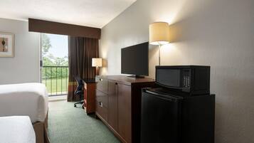A hotel room with a bed, a desk, a television, a microwave, and a refrigerator.