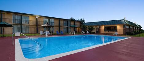 Un hotel con piscina, mobiliario exterior y un patio cubierto.