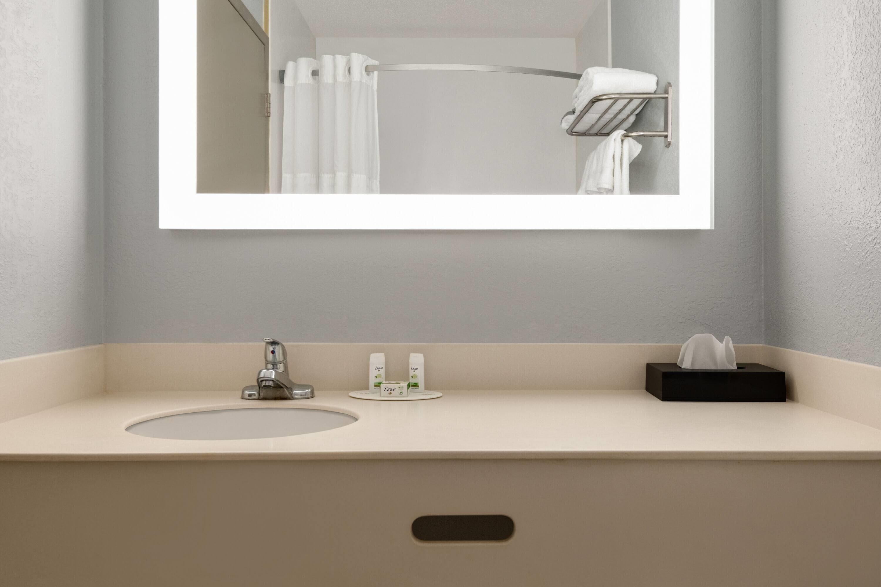 A bathroom with a sink, mirror, and towel rack.