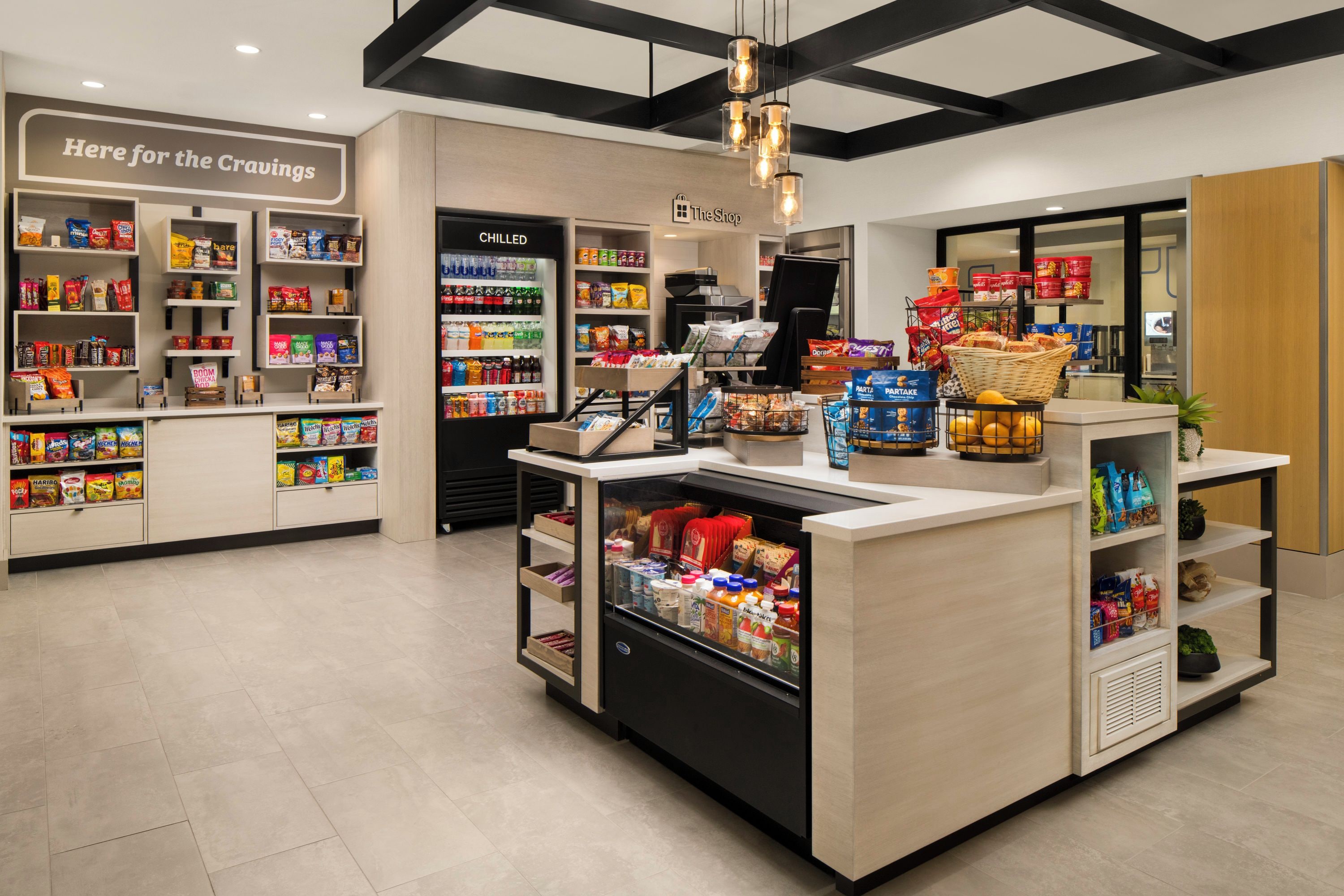 L'intérieur d'une épicerie, avec des rayons réfrigérés, des allées de produits d'épicerie fine et une zone de caisses.