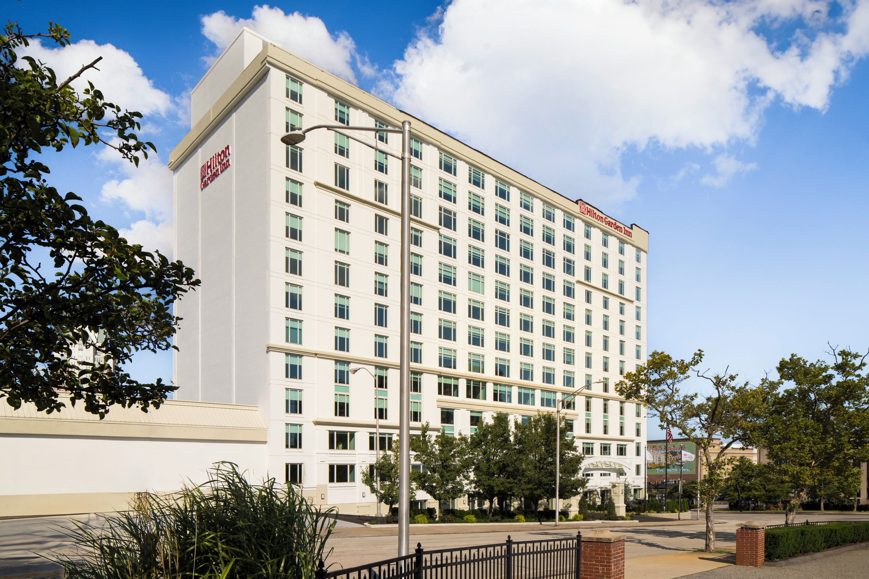 Ett hotell med flera våningar, en vit fasad och en tydligt synlig Hilton Garden Inn-logotyp.
