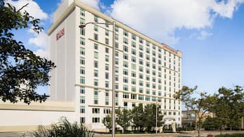 Ett hotell med flera våningar, en vit fasad och en tydligt synlig Hilton Garden Inn-logotyp.