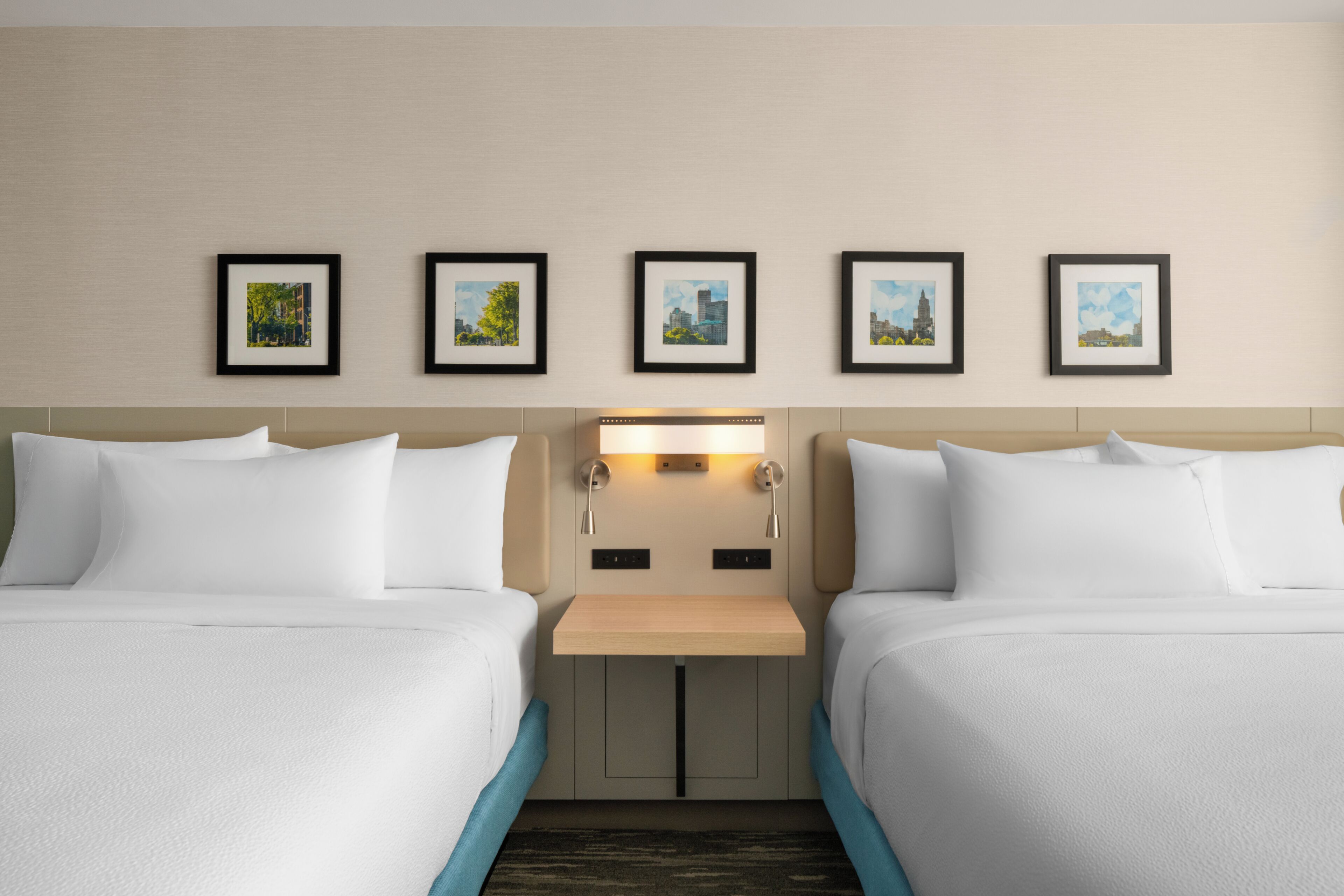 Habitació d'hotel amb dos llits, una taula de nit i una làmpada penjada a la paret.