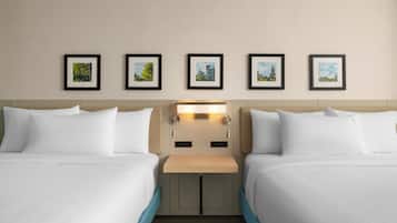 Habitació d'hotel amb dos llits, una taula de nit i una làmpada penjada a la paret.