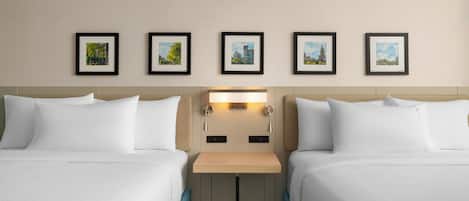 Habitación de hotel con dos camas, una mesita de noche y una lámpara en la pared.