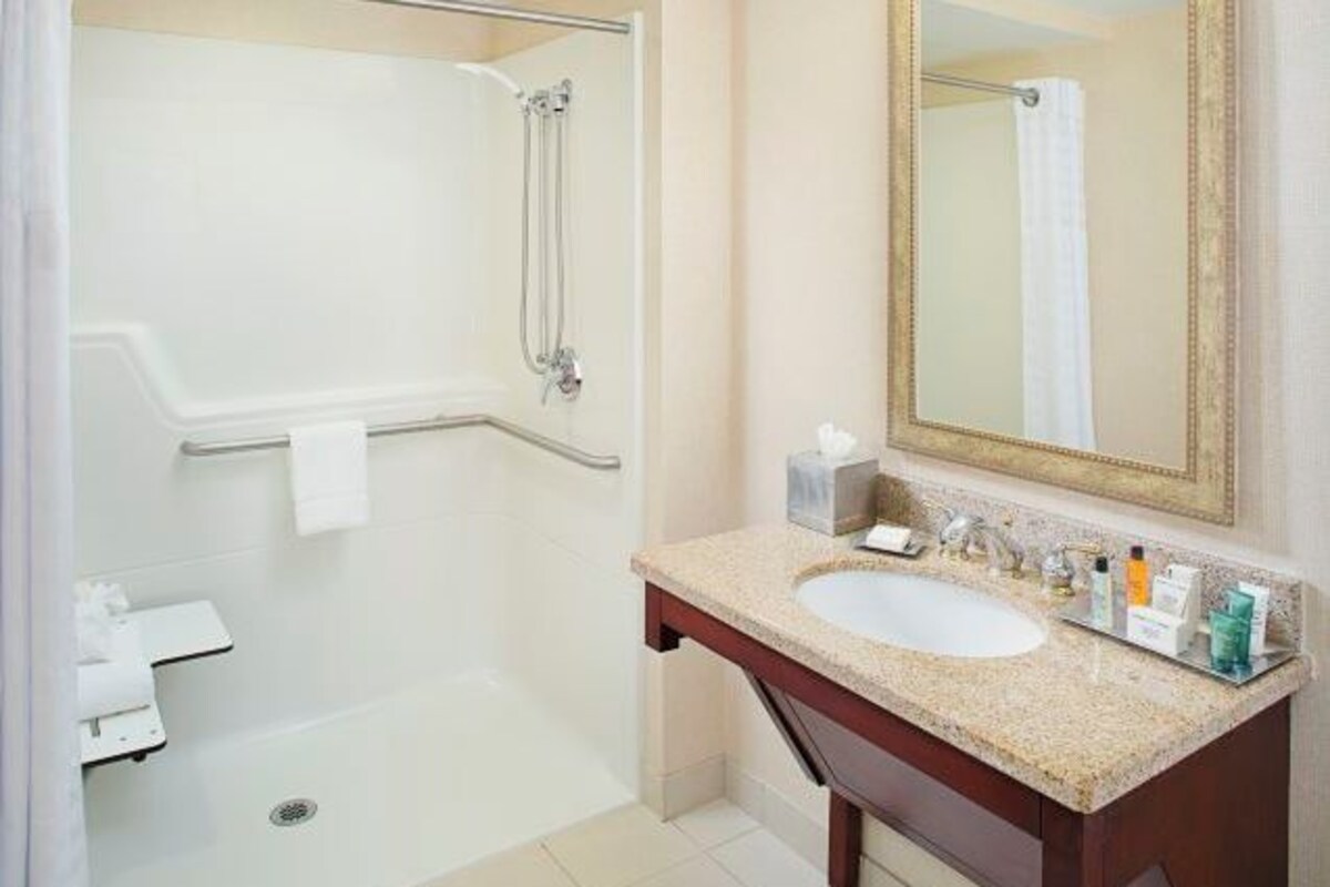 Un baño con ducha, lavamanos y espejo.