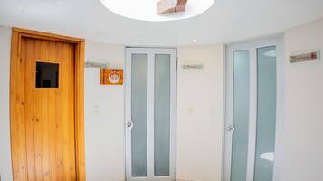 A corner room with a wooden door, a frosted glass door, and a ceiling light fixture.