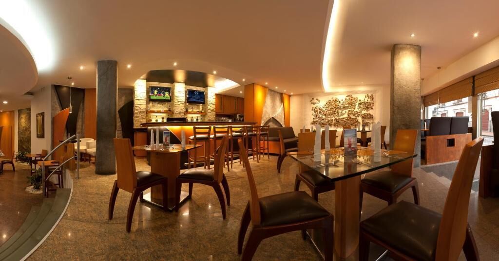 Una hall moderna di un hotel con un’area bar, posti a sedere e una scalinata.