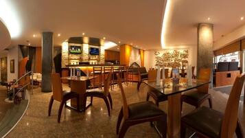 Una hall moderna di un hotel con un’area bar, posti a sedere e una scalinata.