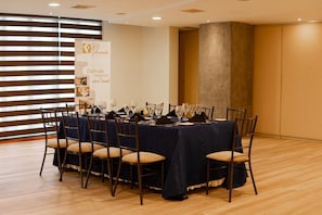 A conference room with a long table set for a meeting, equipped with chairs and a banner advertising the hotel. - El Dorado Hotel (Cuenca)