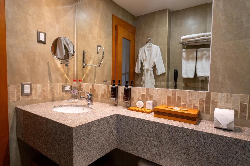 Een moderne badkamer met een granieten aanrechtblad, een wastafel, een spiegel en een handdoekhouder.