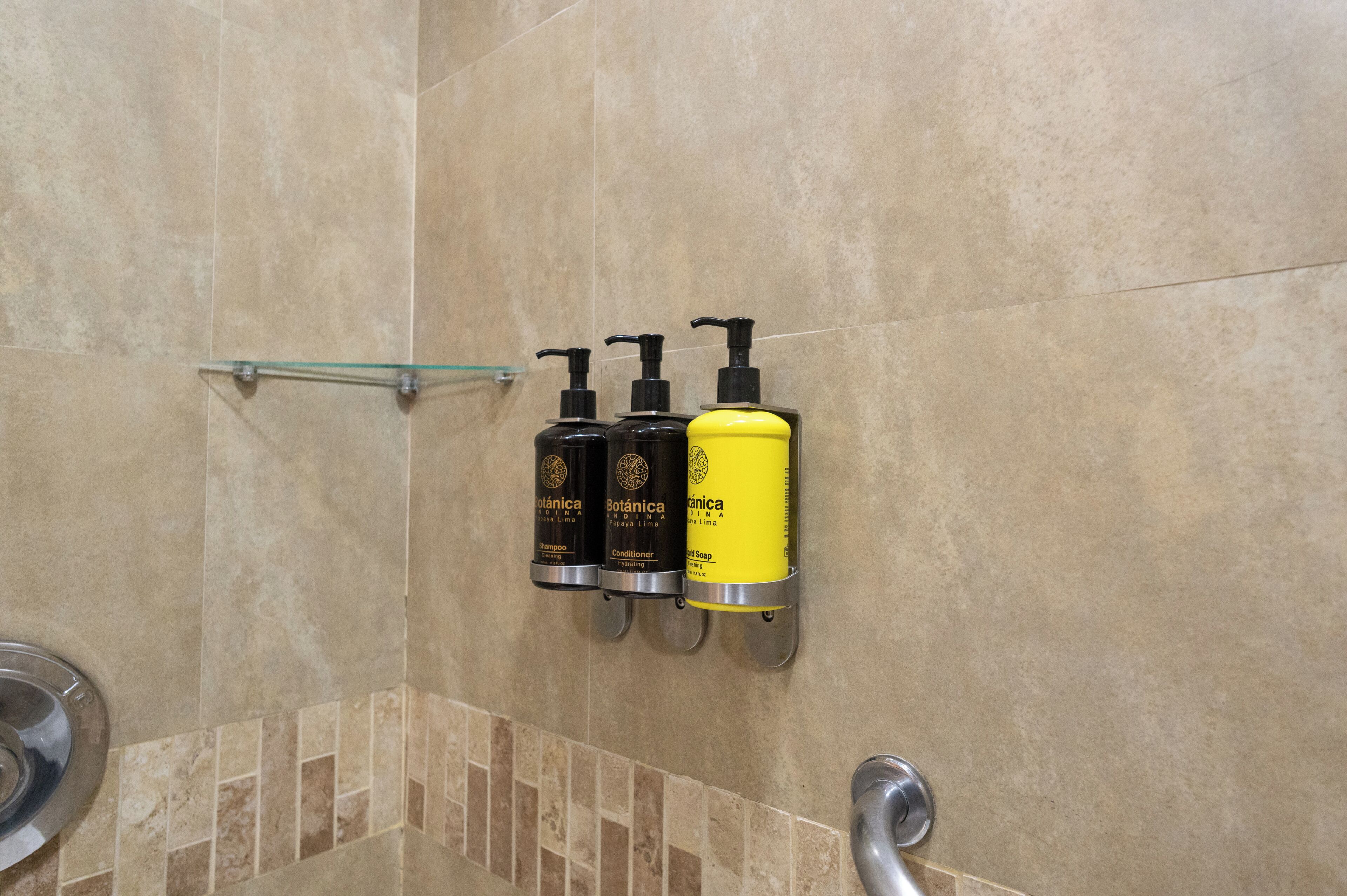 Une salle de bain avec trois étagères murales pour les articles de toilette, une étagère en verre et un espace douche.