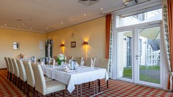A dining room with a checkered floor, a long table set for a meal, and a view through a glass door.
