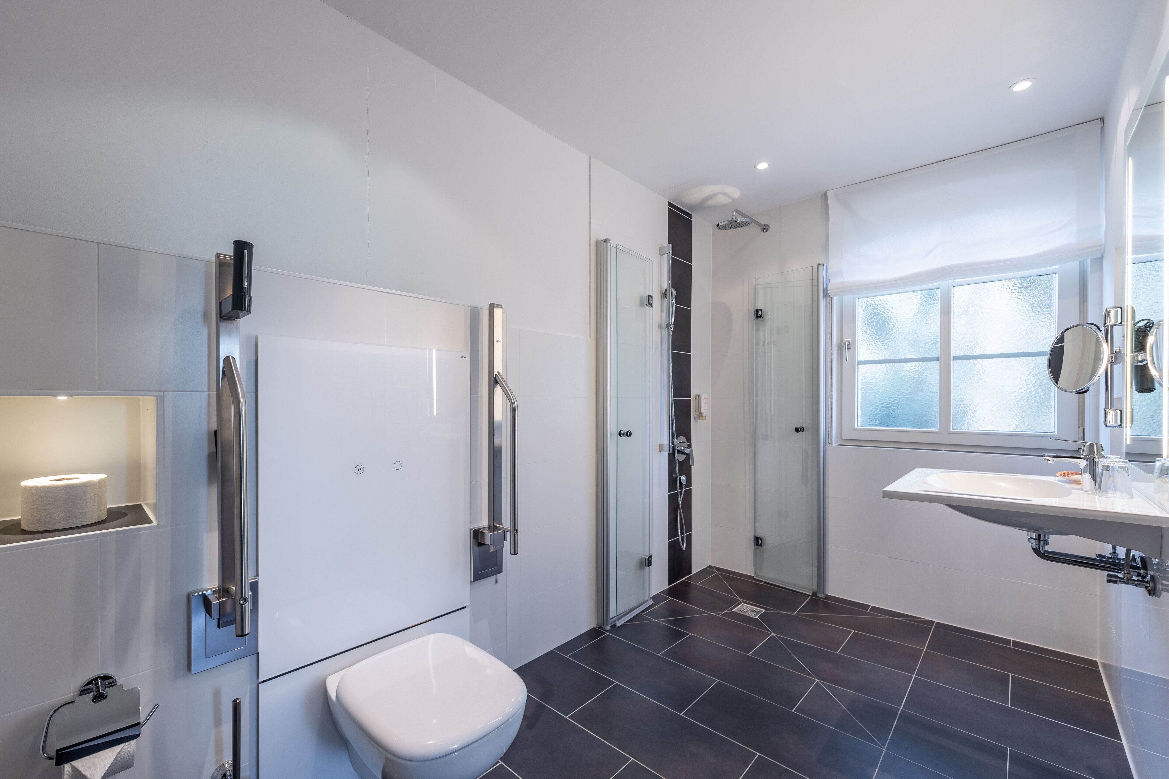 Une salle de bain moderne équipée de toilettes, d’un lavabo et d’un espace douche.