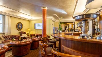 A bar area with leather seating, a large copper column, and a bar counter with a large metal bowl.