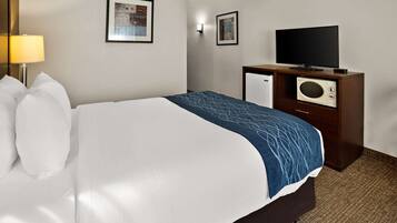 Una habitación de hotel con una cama, televisión, microondas y lámpara.