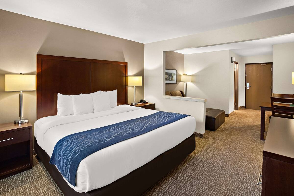 A hotel room with a large bed, two bedside tables with lamps, a desk, and a chair.