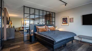 A modern bedroom with a large bed, a desk, and a glass partition.