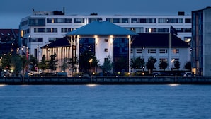 A waterfront hotel with a distinctive blue roof, multiple floors, and a well-lit facade.
