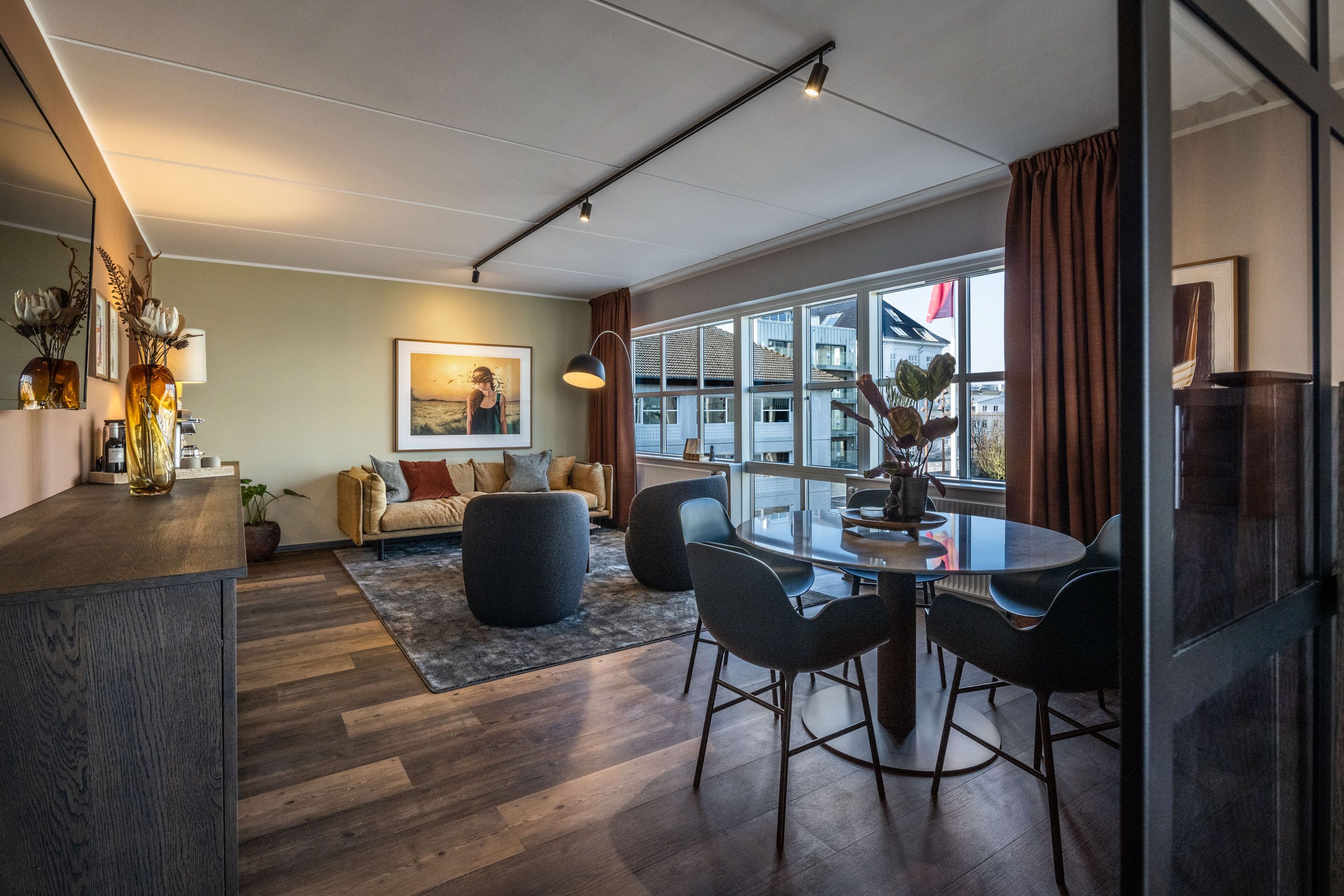 Ein modernes Wohnzimmer mit Essbereich, großen Fenstern und Blick auf die Stadt.