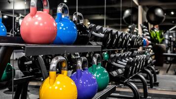 Kettlebells de varios colores dispuestos en un soporte en un gimnasio.